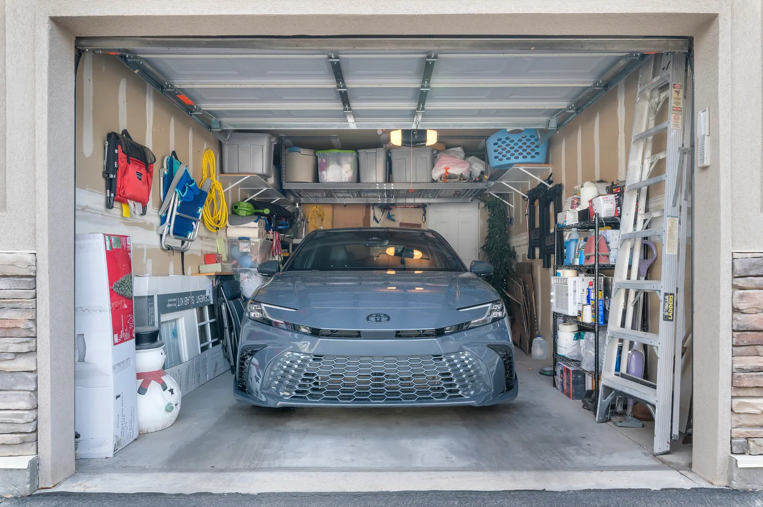 Single-car garage featuring a concrete floor, exposed wood-finish walls, and overhead lighting