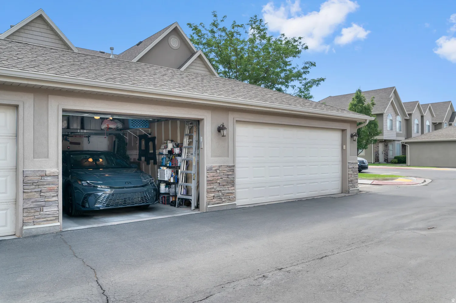 Attached two-car garage featuring a paneled door, exterior wall sconce, and stacked stone accents