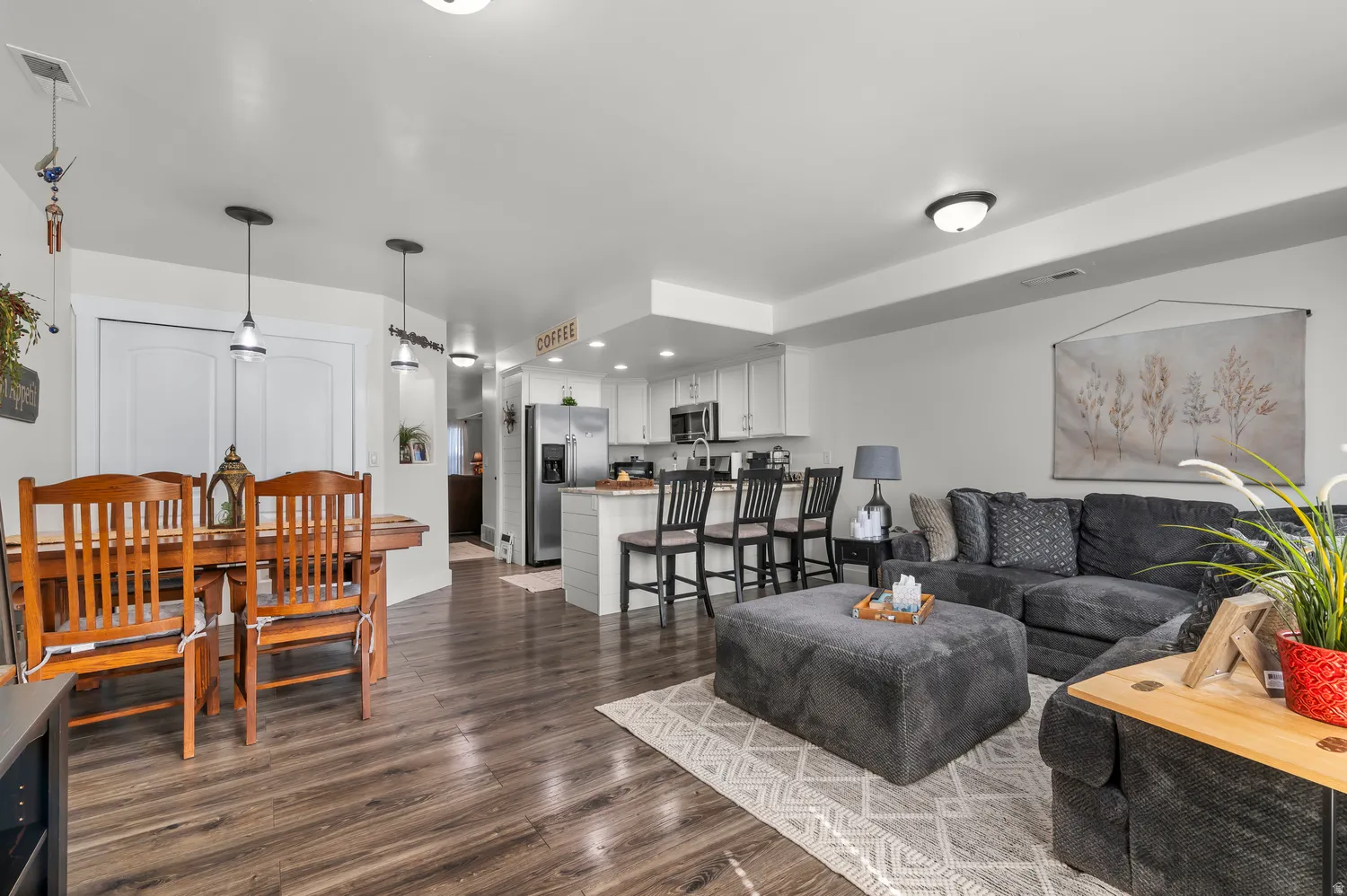Open-concept living area featuring wood-finish flooring, recessed lighting, and a kitchen island with seating