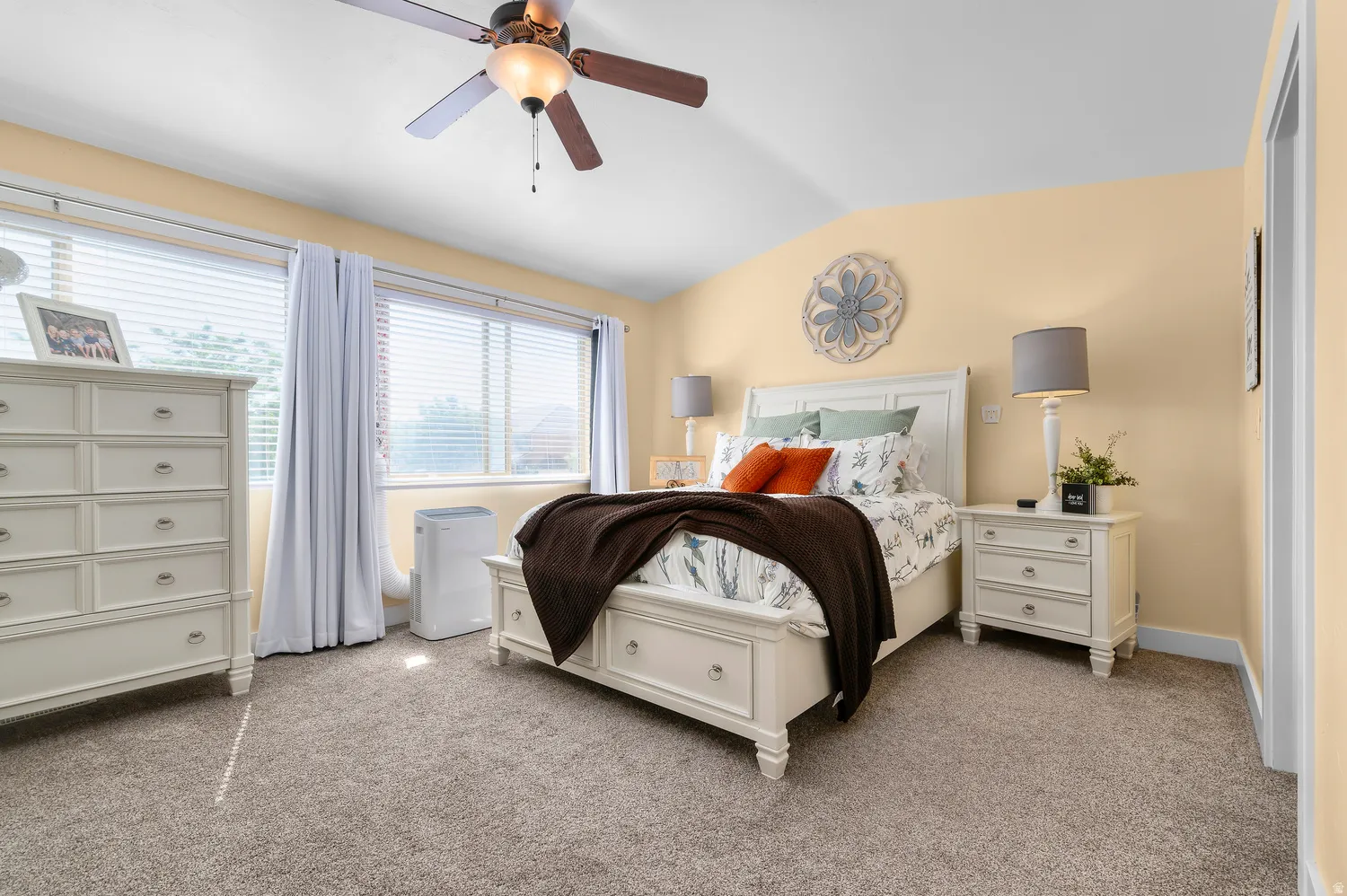Carpeted bedroom with a vaulted ceiling and a ceiling fan with integrated lighting