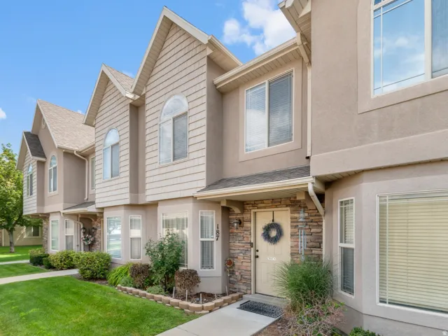 Townhome exterior featuring a stone facade accent, stucco finish, and shaker siding