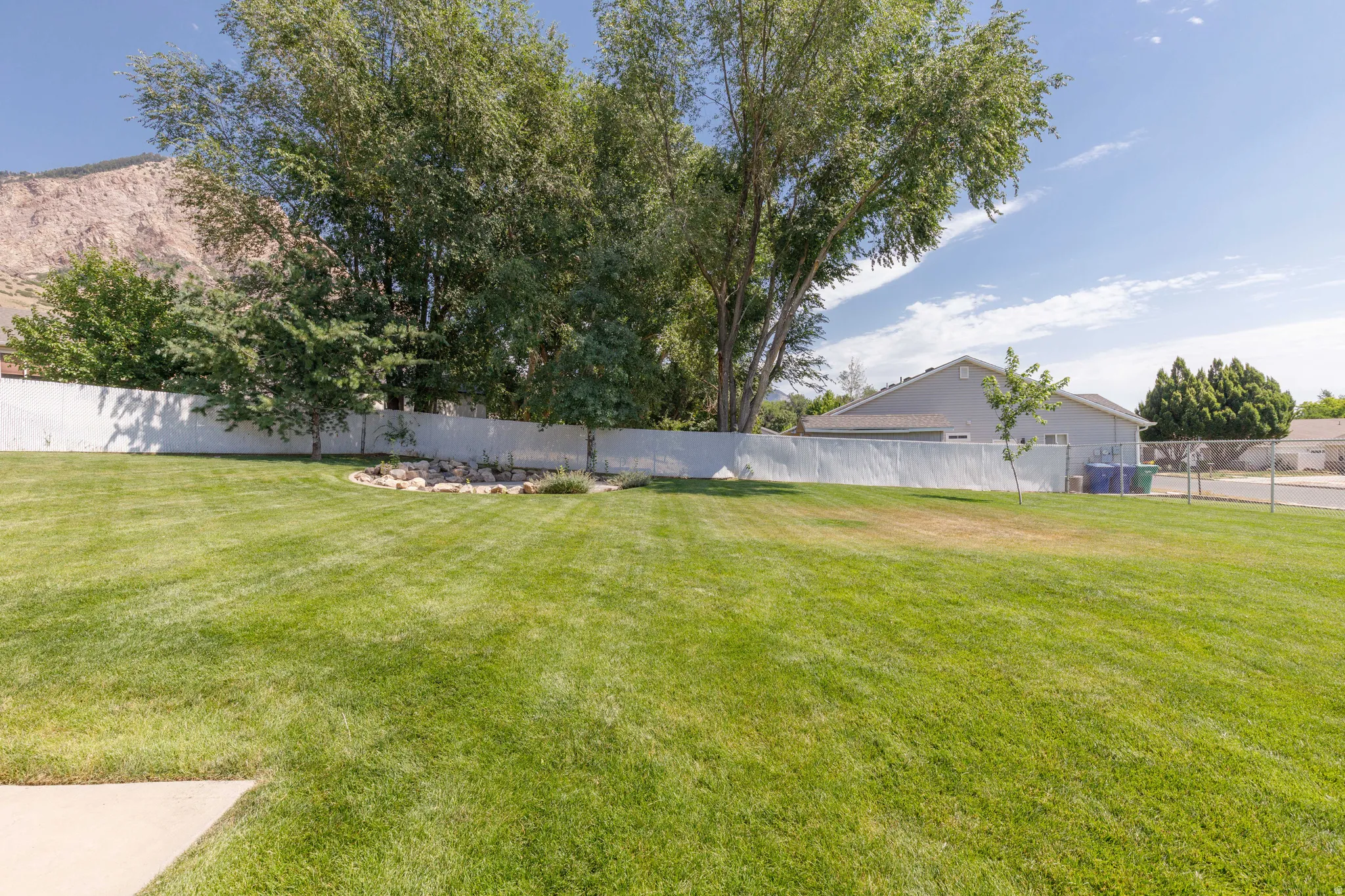 Expansive green lawn with a white privacy fence