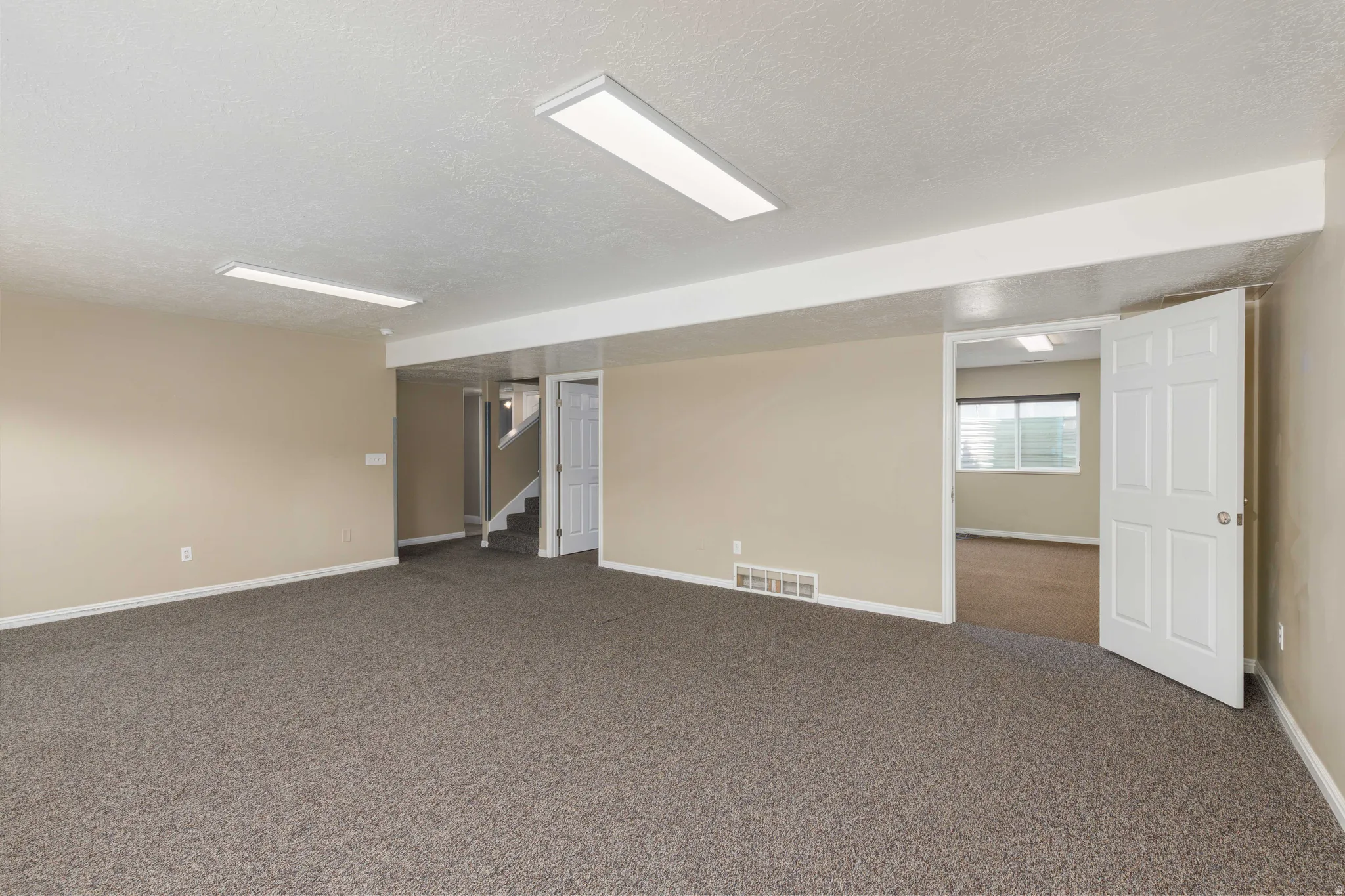 Spacious room featuring neutral-toned walls, recessed lighting, and durable carpeting
