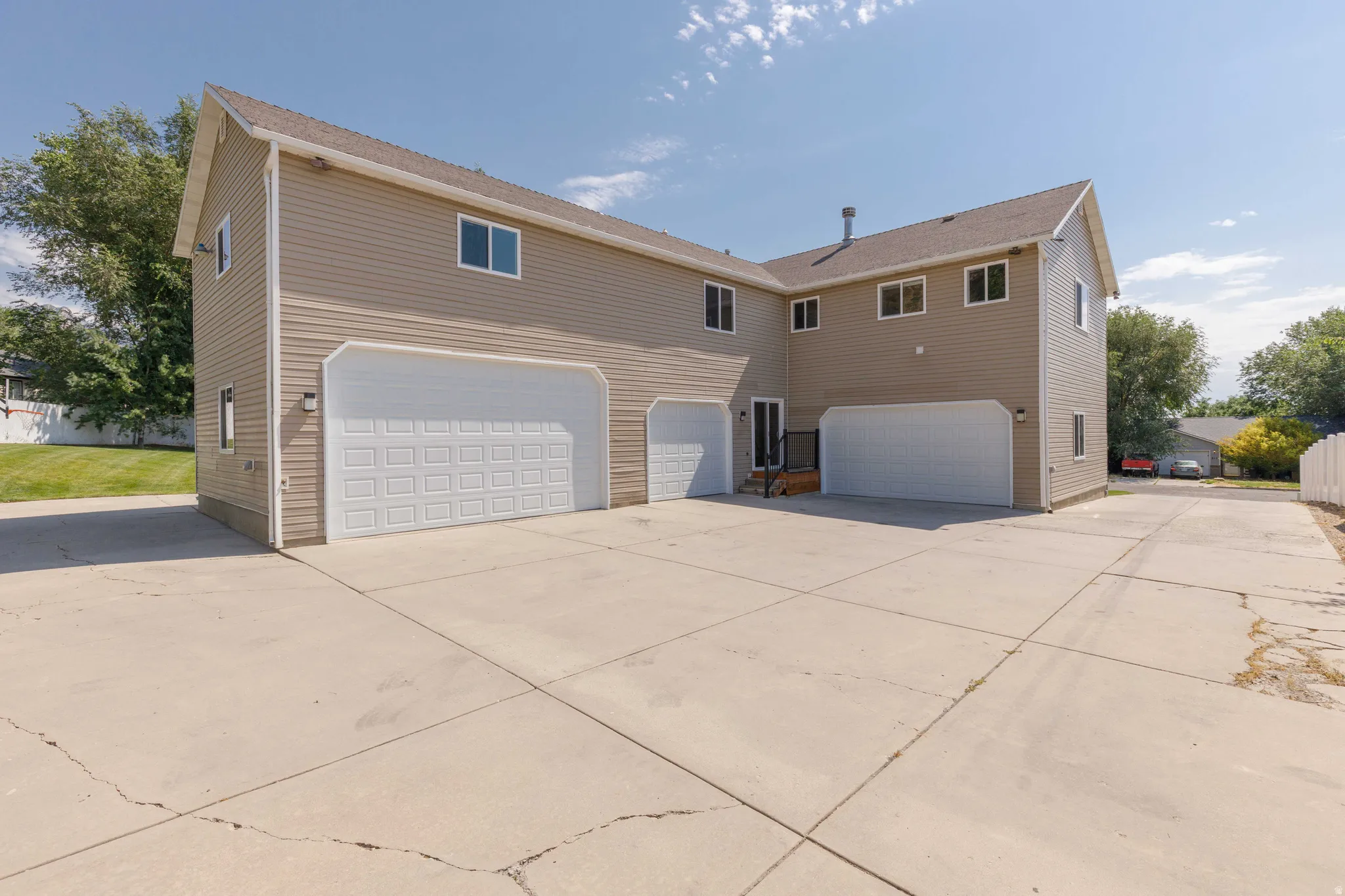 Multi-bay garage exterior with tan siding and white garage doors