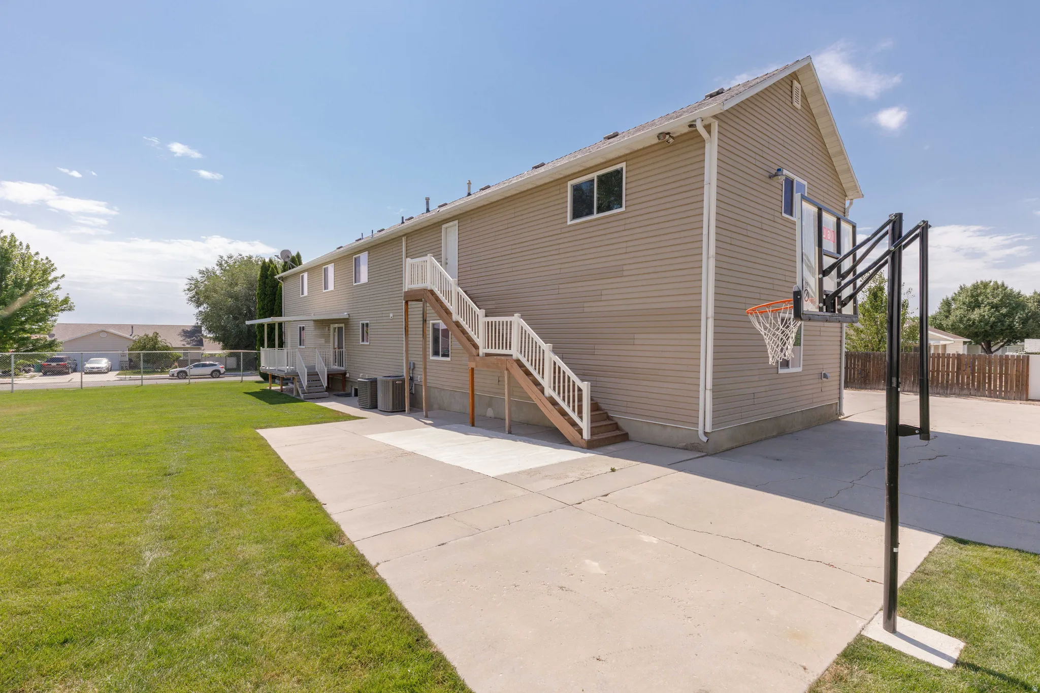 Rear exterior featuring neutral-toned siding, a concrete patio, and a basketball hoop
