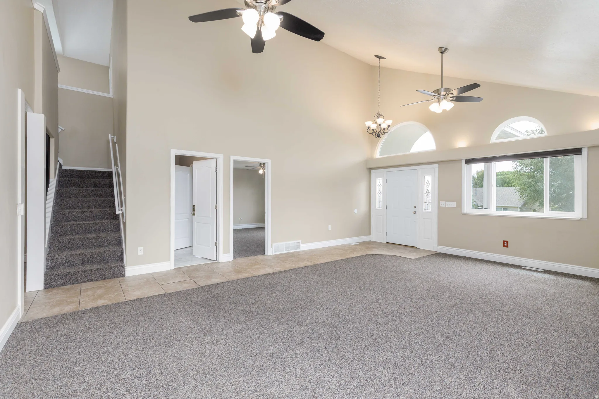 Spacious living area featuring vaulted ceilings, a tiled entry, and carpeted flooring