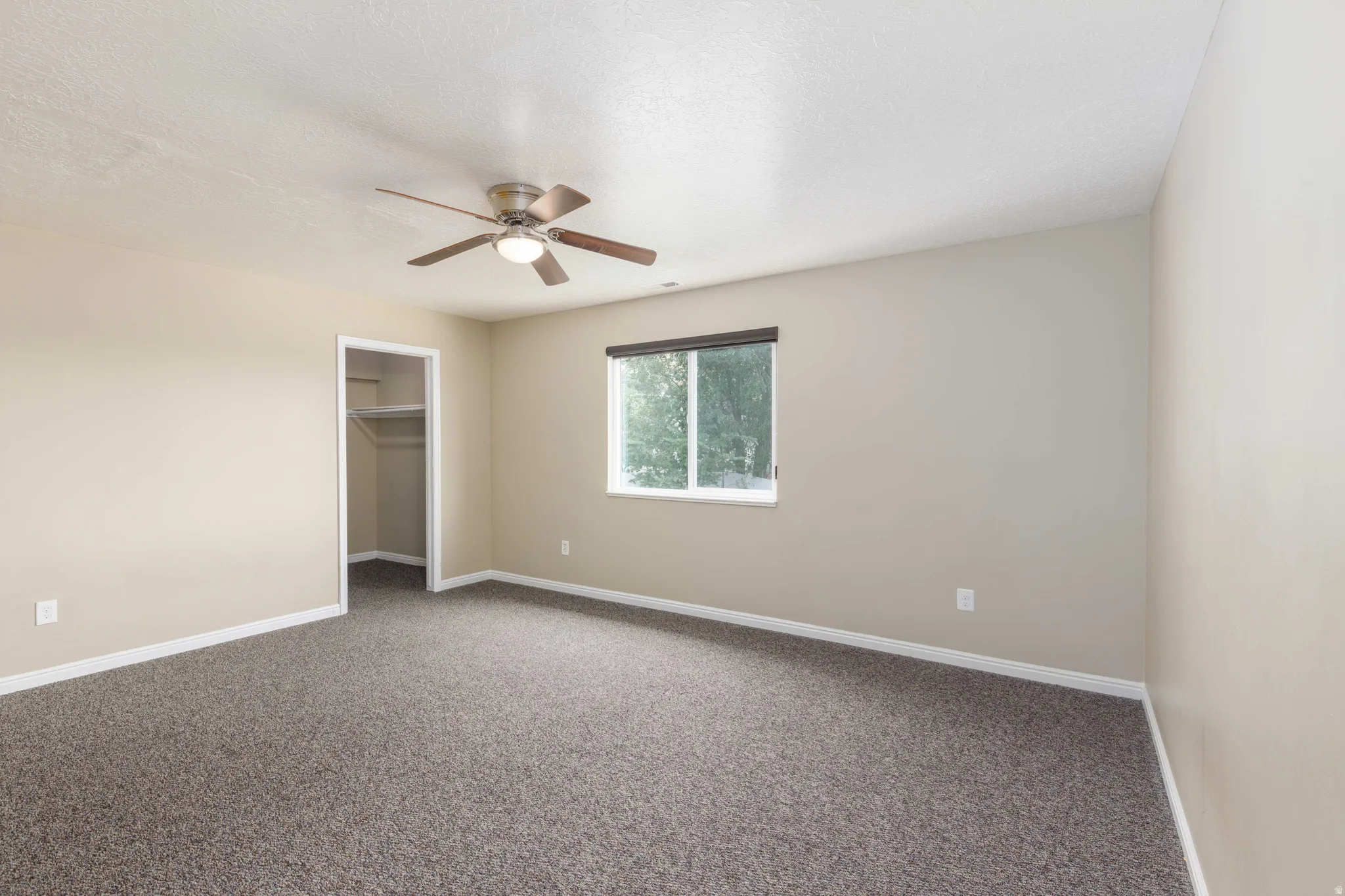 Room featuring neutral-toned walls, dark patterned carpet, and white trim