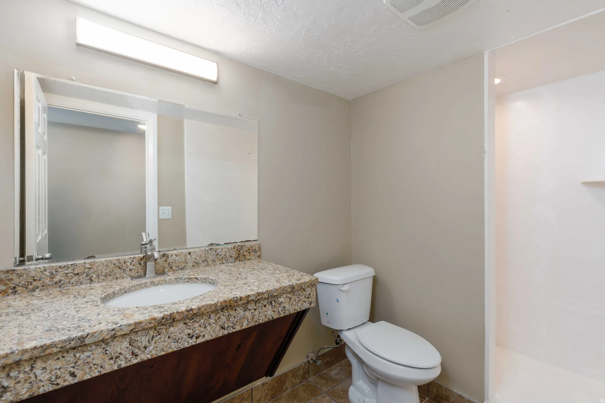 Bathroom featuring a vanity with granite countertop, integrated sink, and dark wood-finish cabinetry