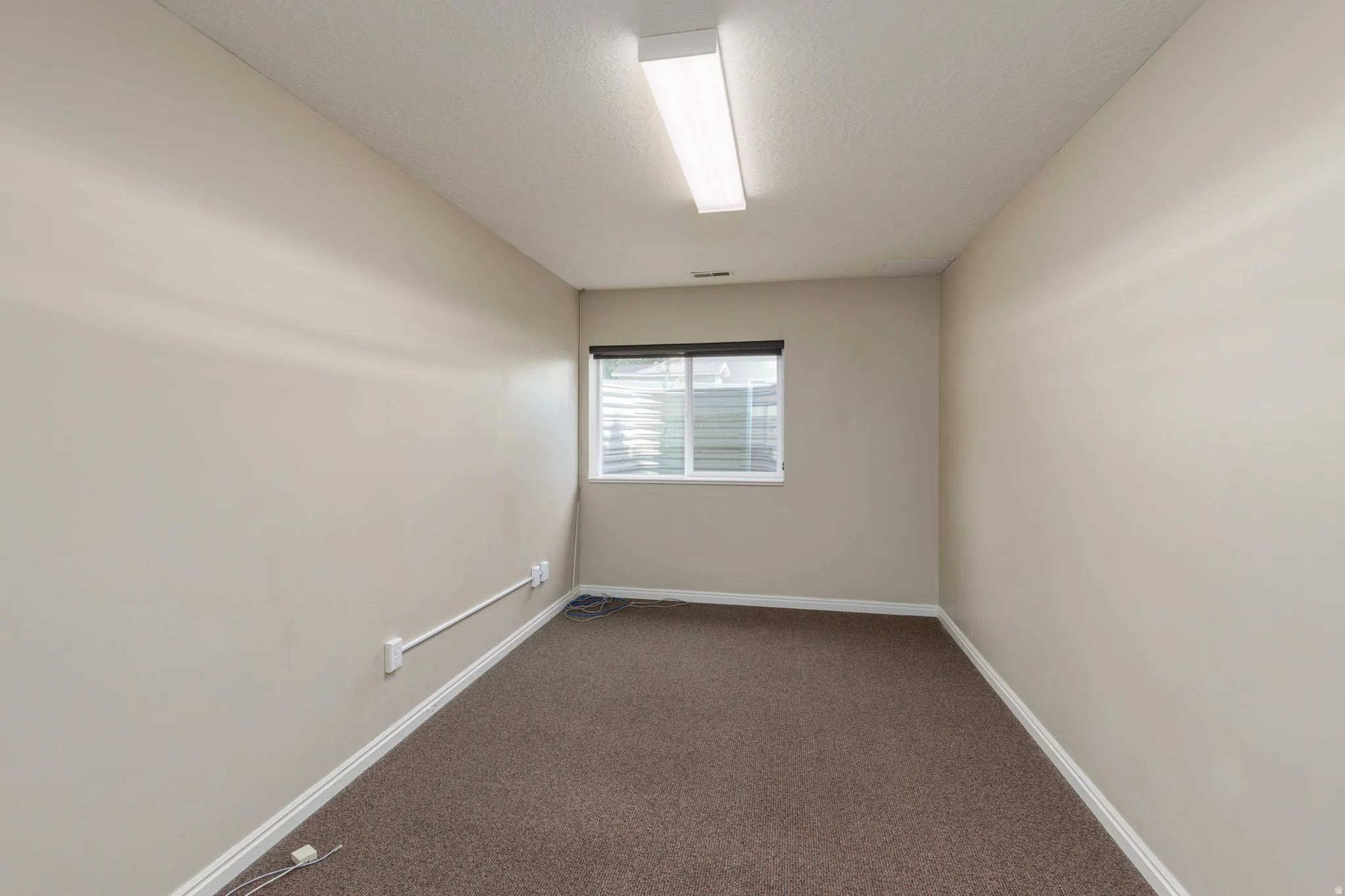 Interior space featuring neutral painted walls, brown carpet flooring, and white baseboards