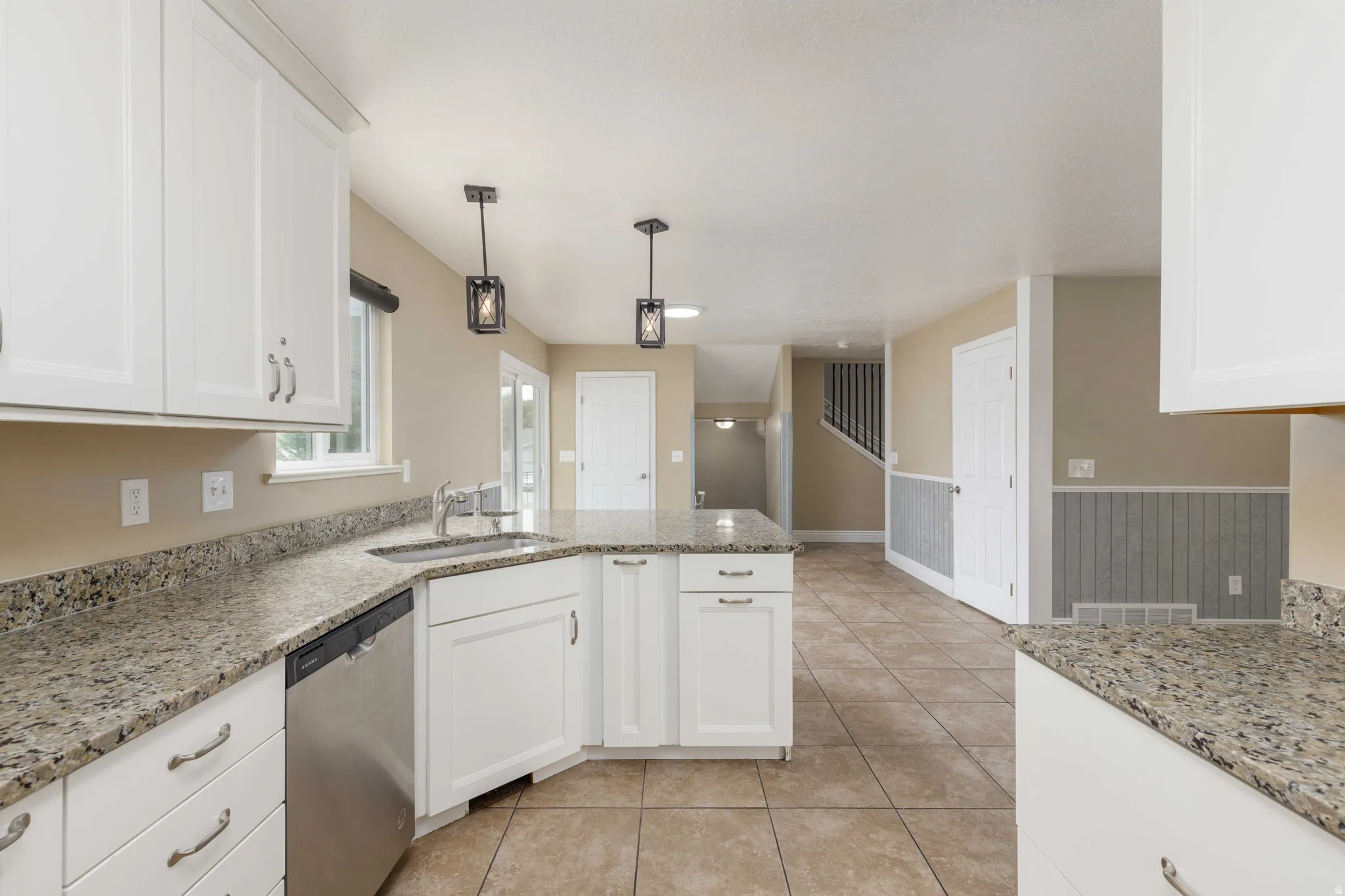 Kitchen featuring white cabinetry, light-toned granite countertops, stainless steel appliances, and tile flooring