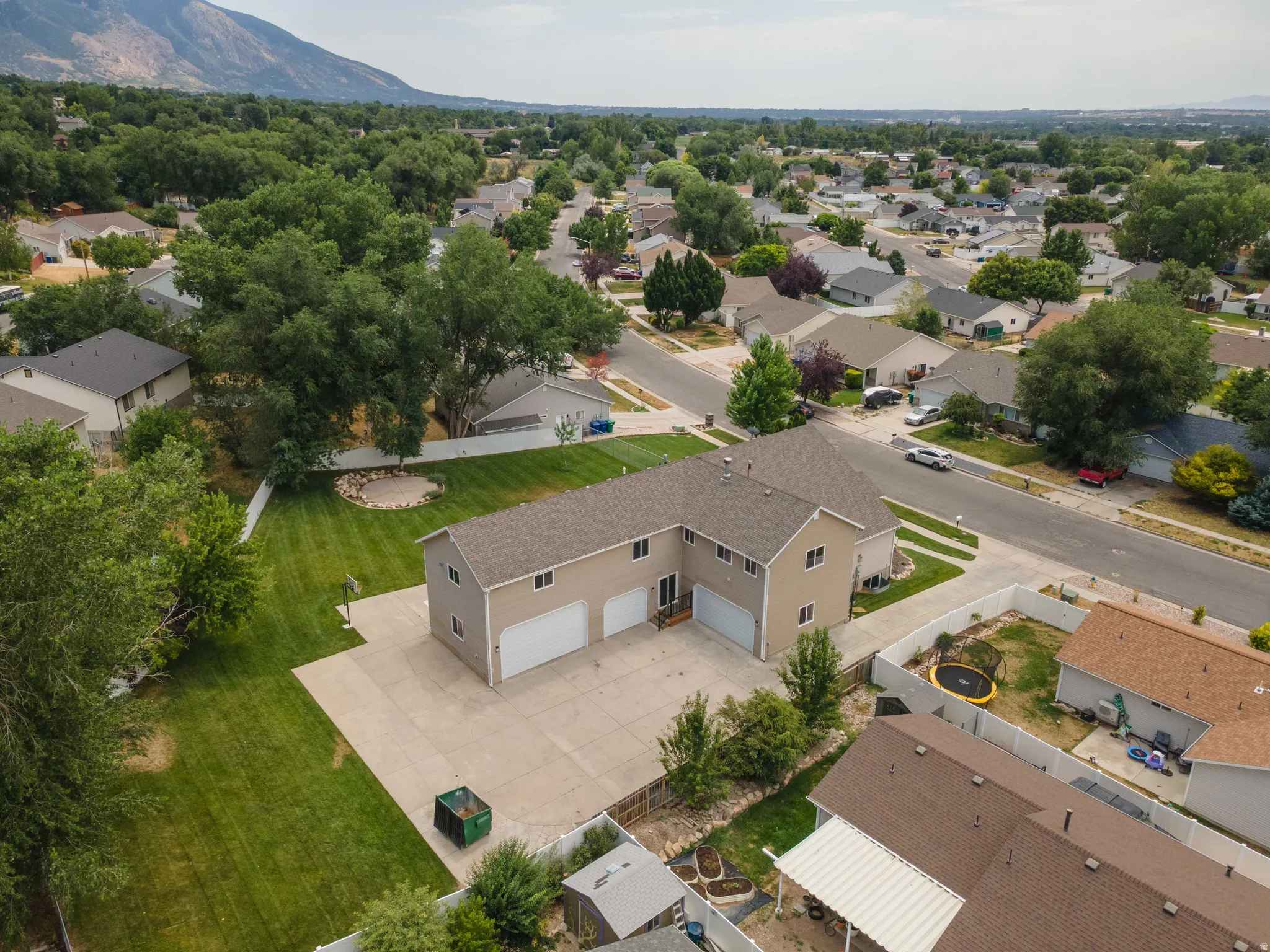Two-story residence featuring a neutral-toned exterior, multiple garage bays, and a large concrete driveway