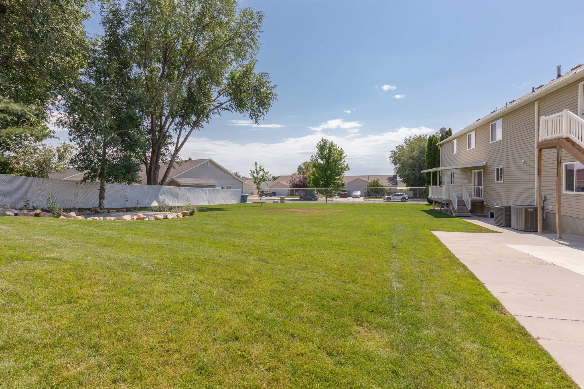 Expansive lawn area featuring a concrete patio and a two-story exterior with a deck