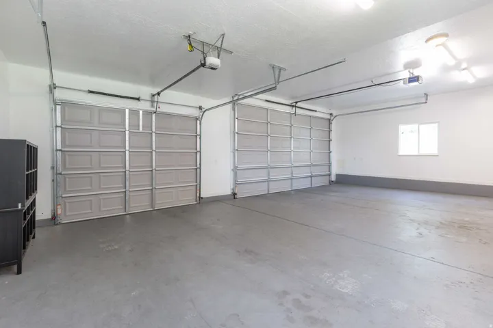 Spacious two-car garage featuring a concrete floor, two individual garage doors, and overhead lighting