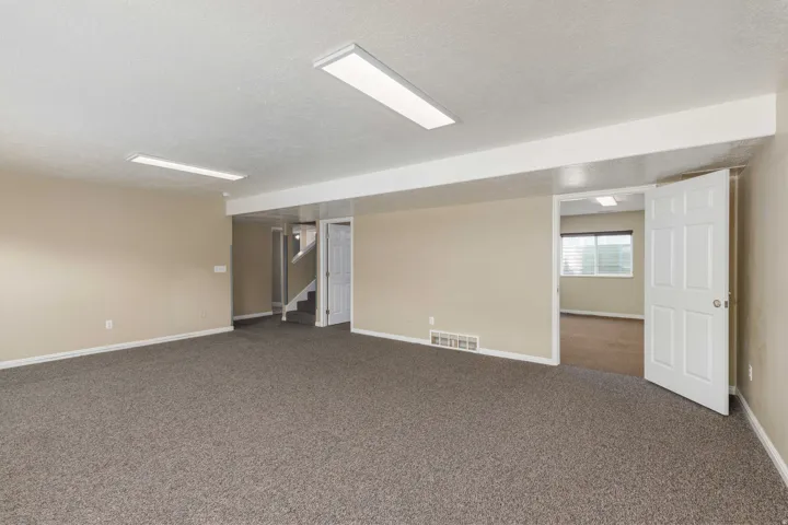 Spacious room featuring neutral-toned walls, recessed lighting, and durable carpeting