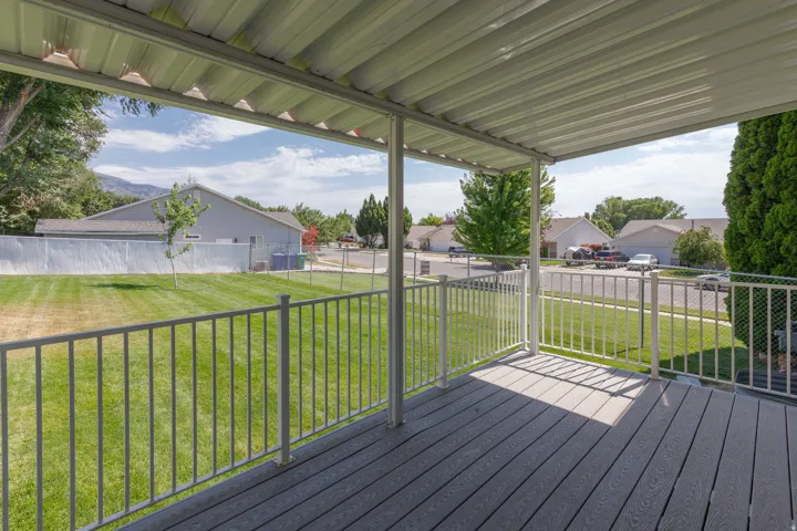 Covered deck featuring composite decking and metal railings, overlooking a fenced backyard and residential street