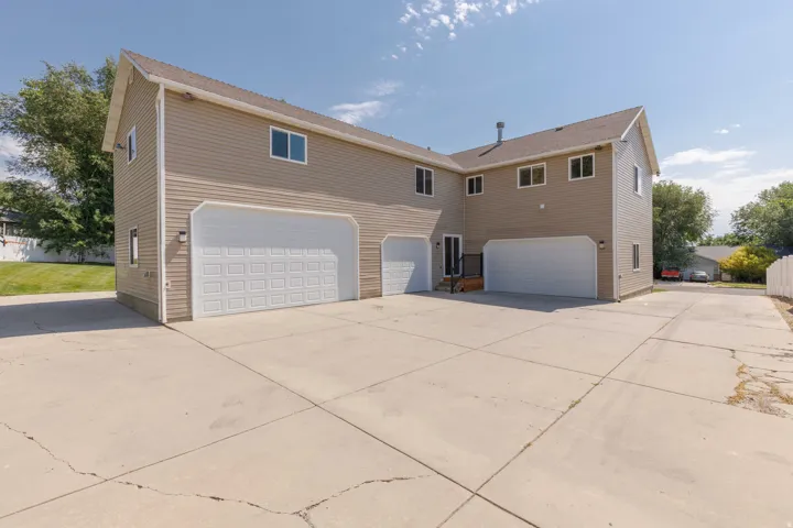Multi-bay garage exterior with tan siding and white garage doors