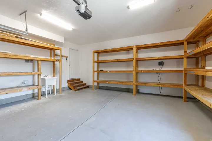 Spacious garage featuring extensive built-in wooden shelving, a utility sink, and a multi-level internal entry