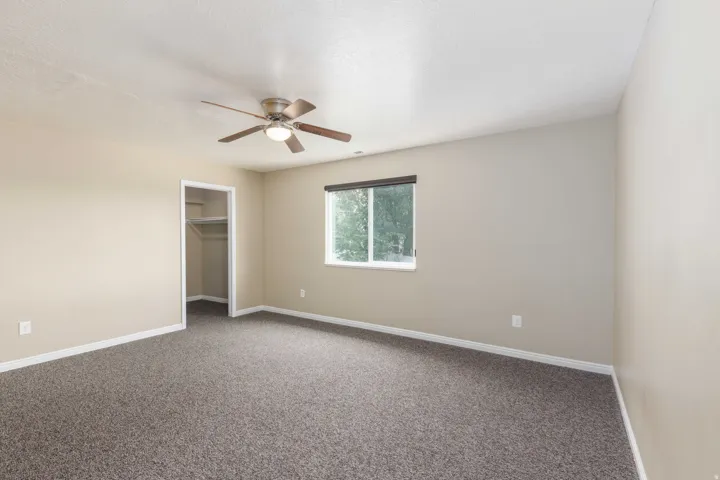 Room featuring neutral-toned walls, dark patterned carpet, and white trim