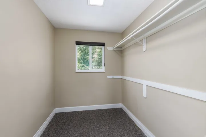 Walk-in closet featuring built-in shelving, hanging rods, and a window for natural light