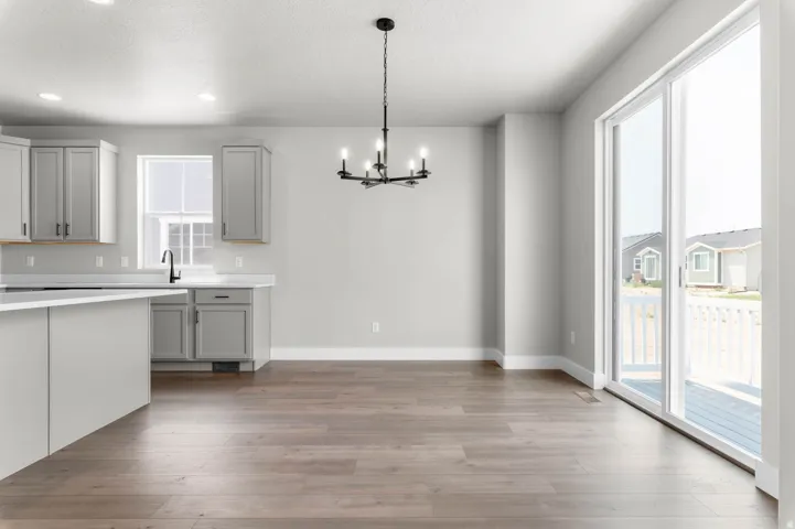 Open-concept living area featuring wood-finish flooring, a modern black chandelier, and a kitchen island with a white countertop