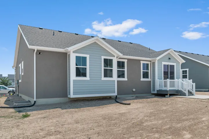 Rear exterior featuring a gray stucco finish and light blue siding accents
