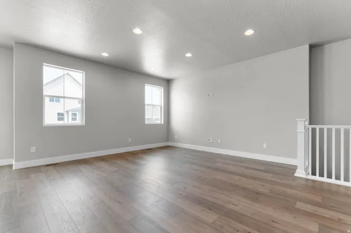 Spacious room featuring wood-finish flooring, recessed lighting, and two large windows providing natural illumination