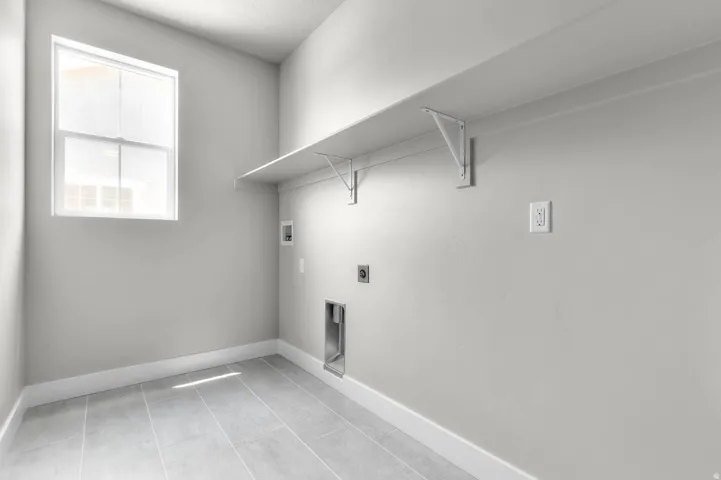 Utility room featuring a window, tile flooring, wall shelving, and appliance hookups