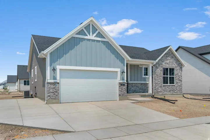 Contemporary single-story residence featuring a two-car garage, stone and siding exterior, a covered entryway, and a paved driveway