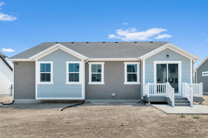 Rear exterior featuring a slider door, deck with white railings, and concrete patio