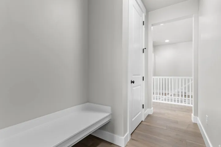 Built-in bench with white trim, wood-finish flooring, recessed lighting, and a white stair railing