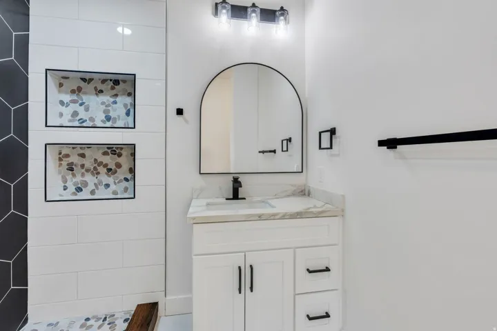 Bathroom vanity featuring a white cabinet, stone-finish countertop, and matte black faucet