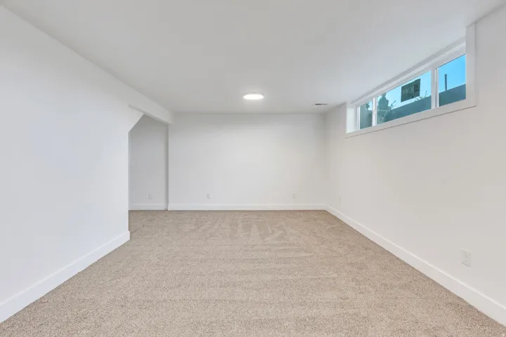 Spacious room featuring neutral carpeting, white walls, recessed ceiling lighting, and horizontal windows