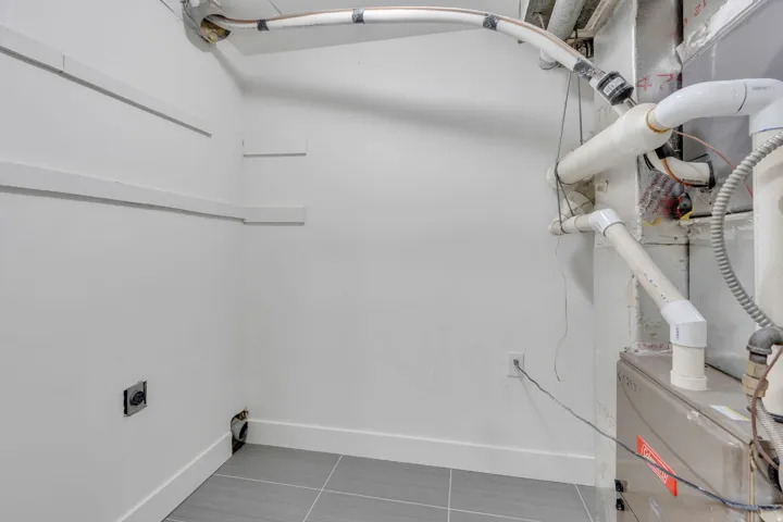 Utility area featuring a furnace, exposed plumbing, and grey tile flooring