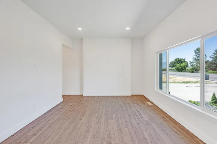 Expansive room with wood-finish flooring, recessed lighting, white walls, and large picture windows