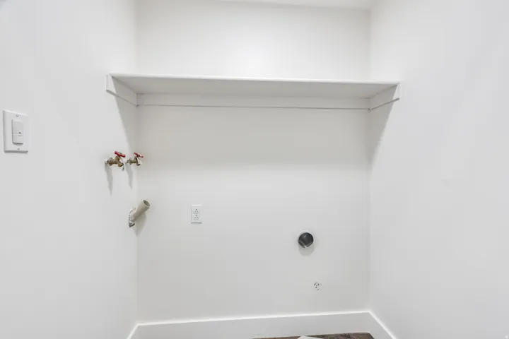 Dedicated laundry area featuring a built-in shelf, white walls, and wood-finish flooring