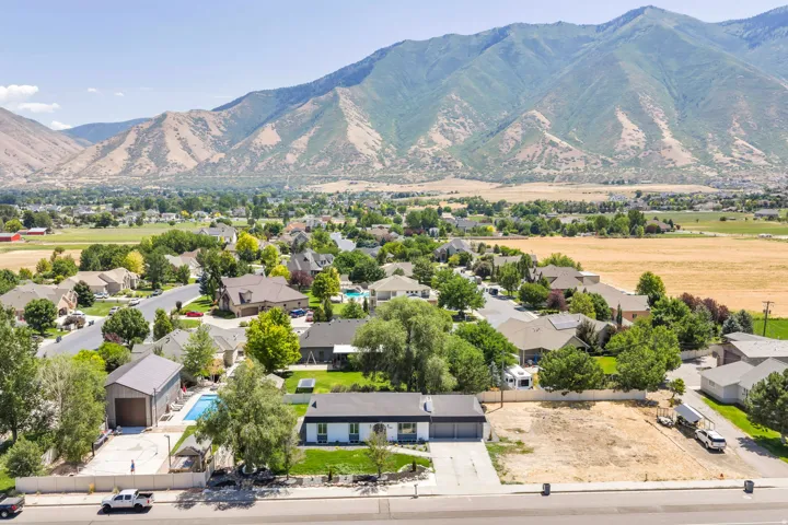 Expansive mountain backdrop framing a residential area with a prominent property featuring a dark-toned roof and light-colored exterior