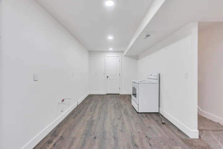 Spacious room featuring wood-finish flooring, recessed lighting, and crisp white walls