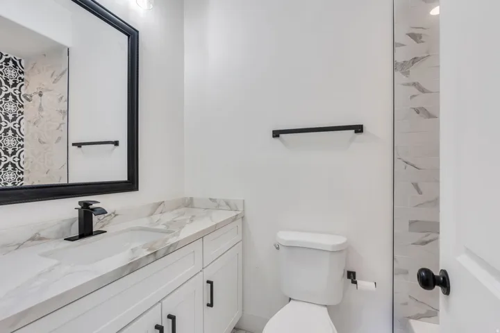 Bathroom featuring a vanity with a rectangular undermount sink, a matte black faucet, and a large framed mirror