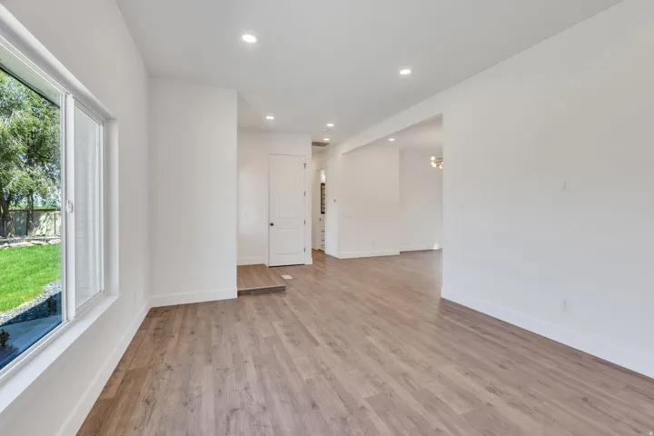 Spacious interior featuring wood-finish flooring, recessed lighting, and a large window overlooking a landscaped yard