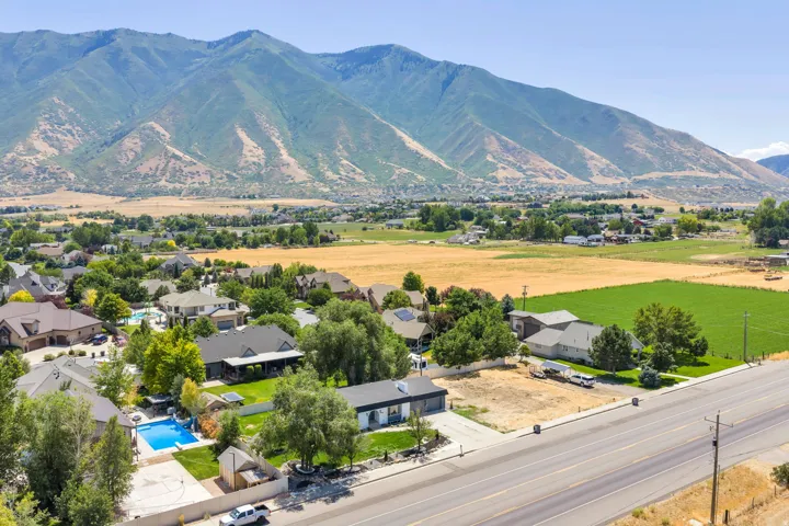 Aerial perspective highlighting mountain vistas, residential properties with mature landscaping, a private swimming pool, and undeveloped land parcels
