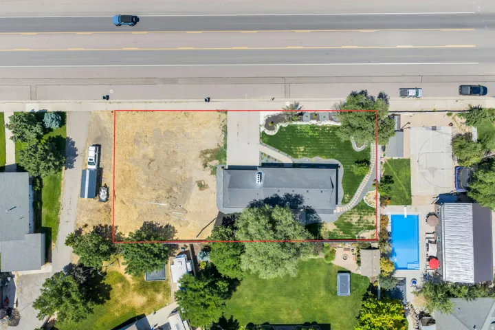 Expansive property featuring a large house, a significant cleared lot, a paved driveway, and established landscaping with mature trees