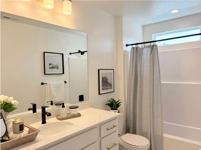Bathroom vanity featuring a solid surface countertop, matte black faucet, and rectangular mirror