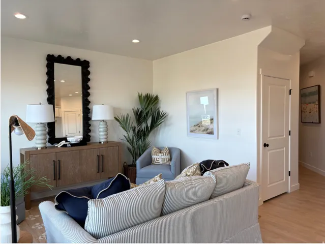 Recessed lighting illuminates this living space, featuring light-colored walls and wood-finish flooring