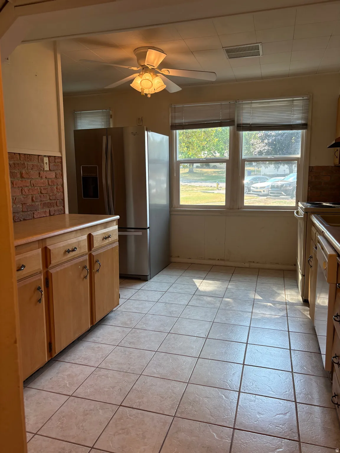 Bright kitchen featuring wood-finish cabinetry, stainless steel appliances, and tile flooring
