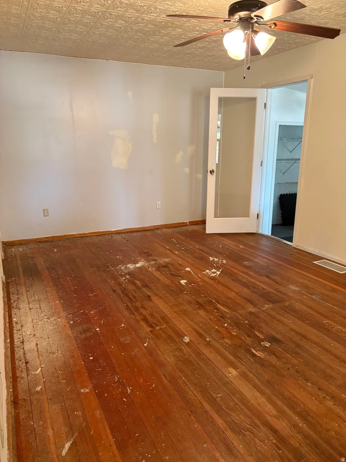 Spacious room featuring hardwood flooring, ceiling fan with integrated lighting, and white interior doors