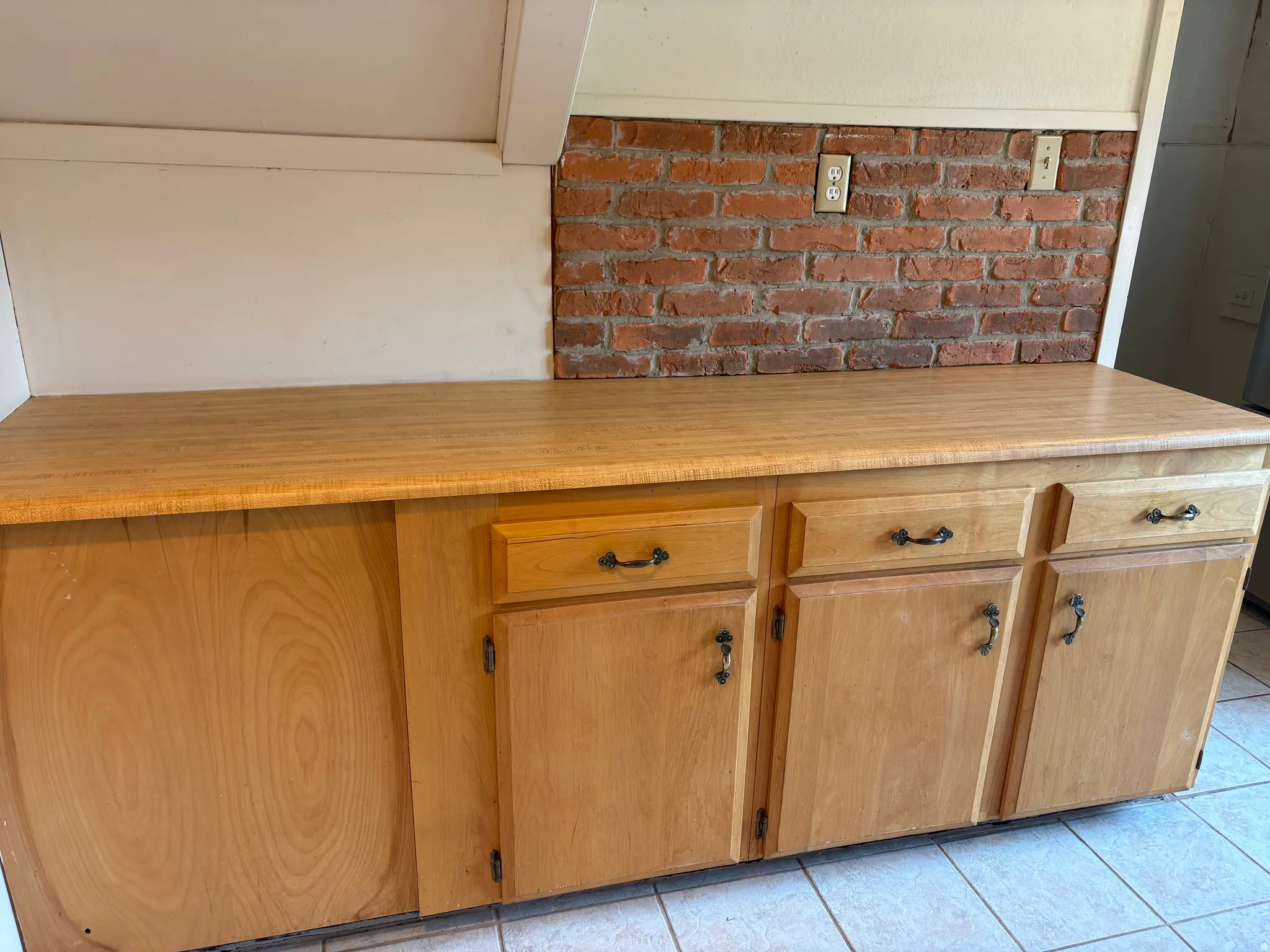 Spacious cabinetry with warm wood-finish construction featuring multiple storage compartments with hardware handles, two functional drawers, and a large curved door panel