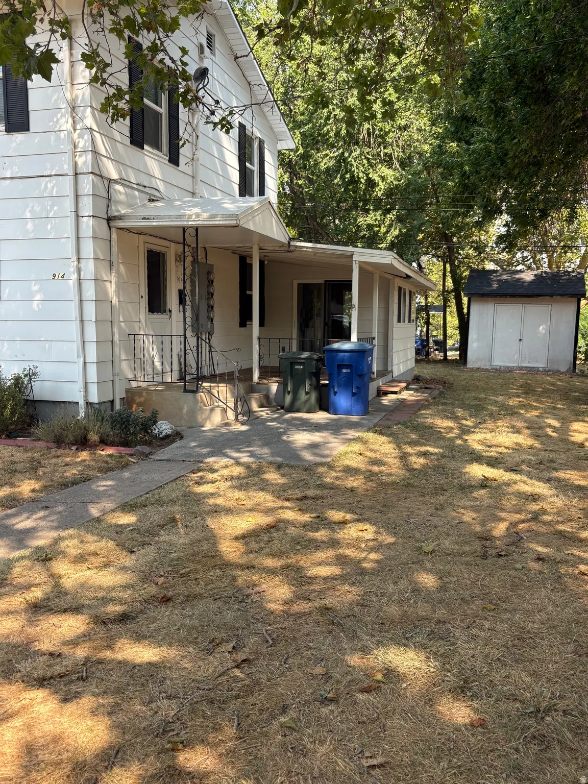 White siding exterior with black window shutters and a covered entry