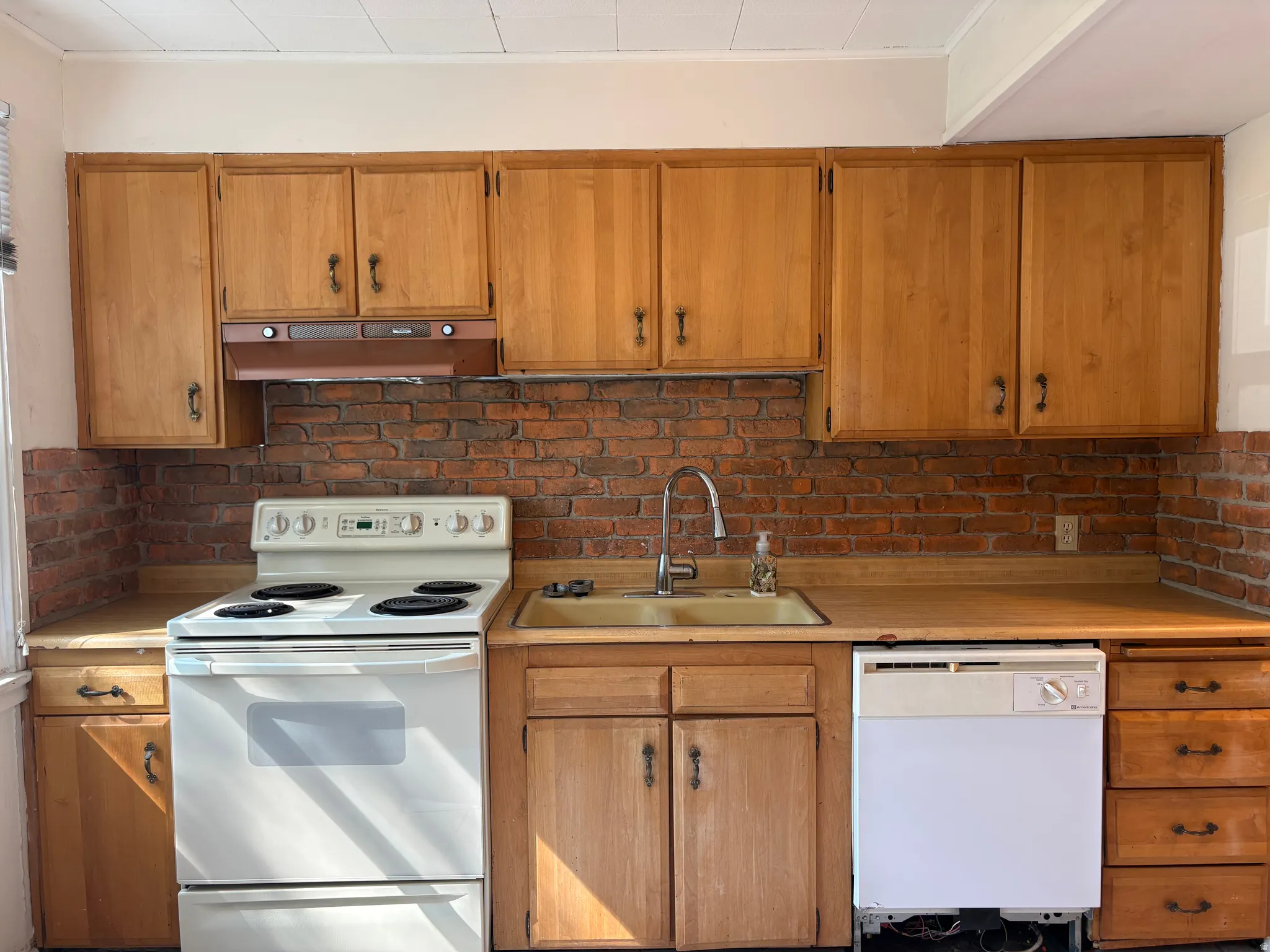 Wood-finish cabinetry paired with a brick backsplash