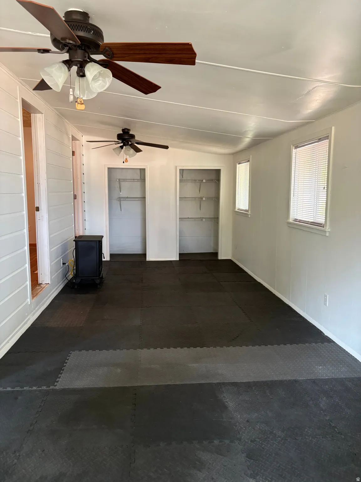 Spacious interior with dual ceiling fans, recessed lighting throughout, and dark composite flooring