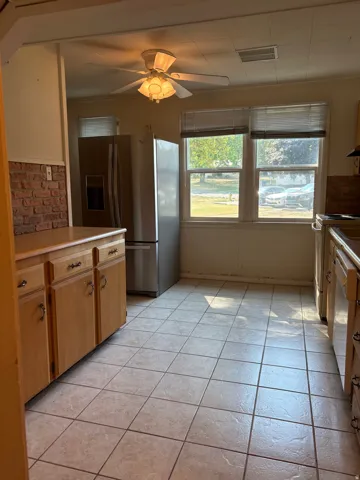 Bright kitchen featuring wood-finish cabinetry, stainless steel appliances, and tile flooring